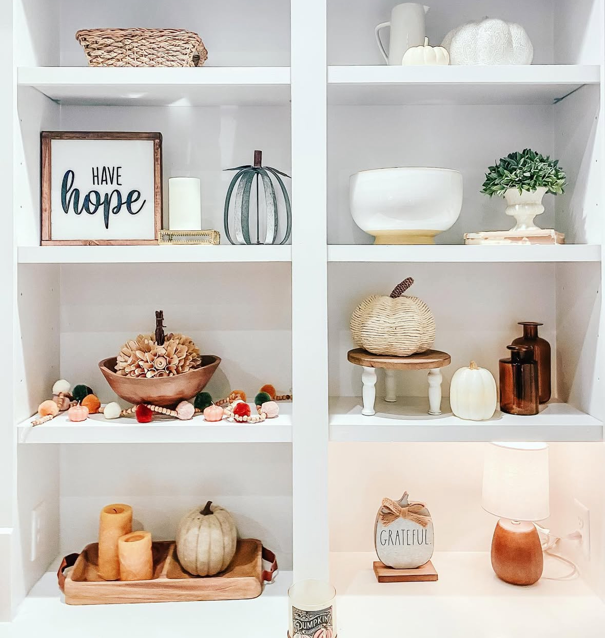 White built-ins with “Have hope” sign, woven and ceramic pumpkins, small lamp, and neutral garland.
