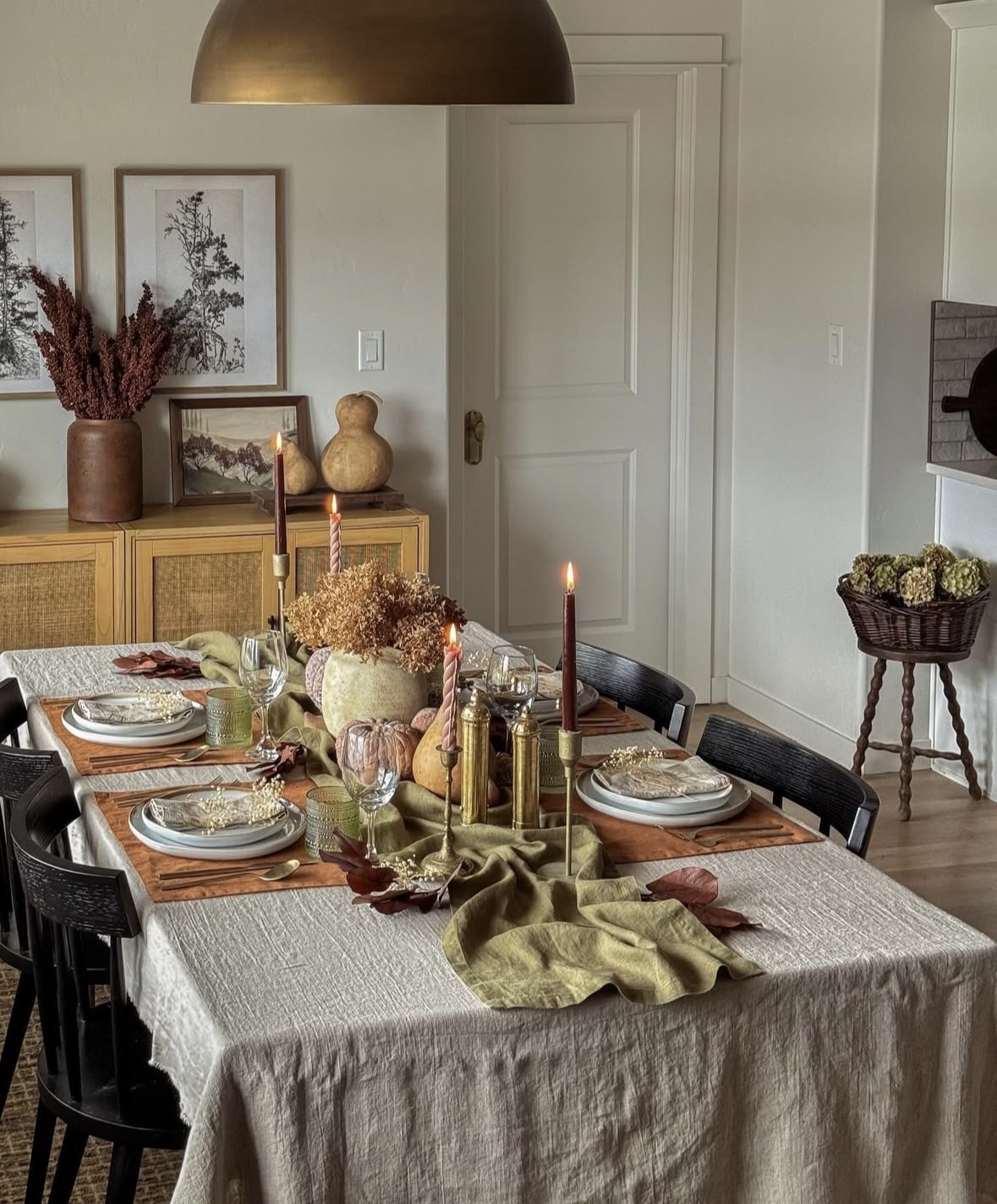 Earthy fall tablescape with olive runner, brass accents, and mottled pumpkins.
