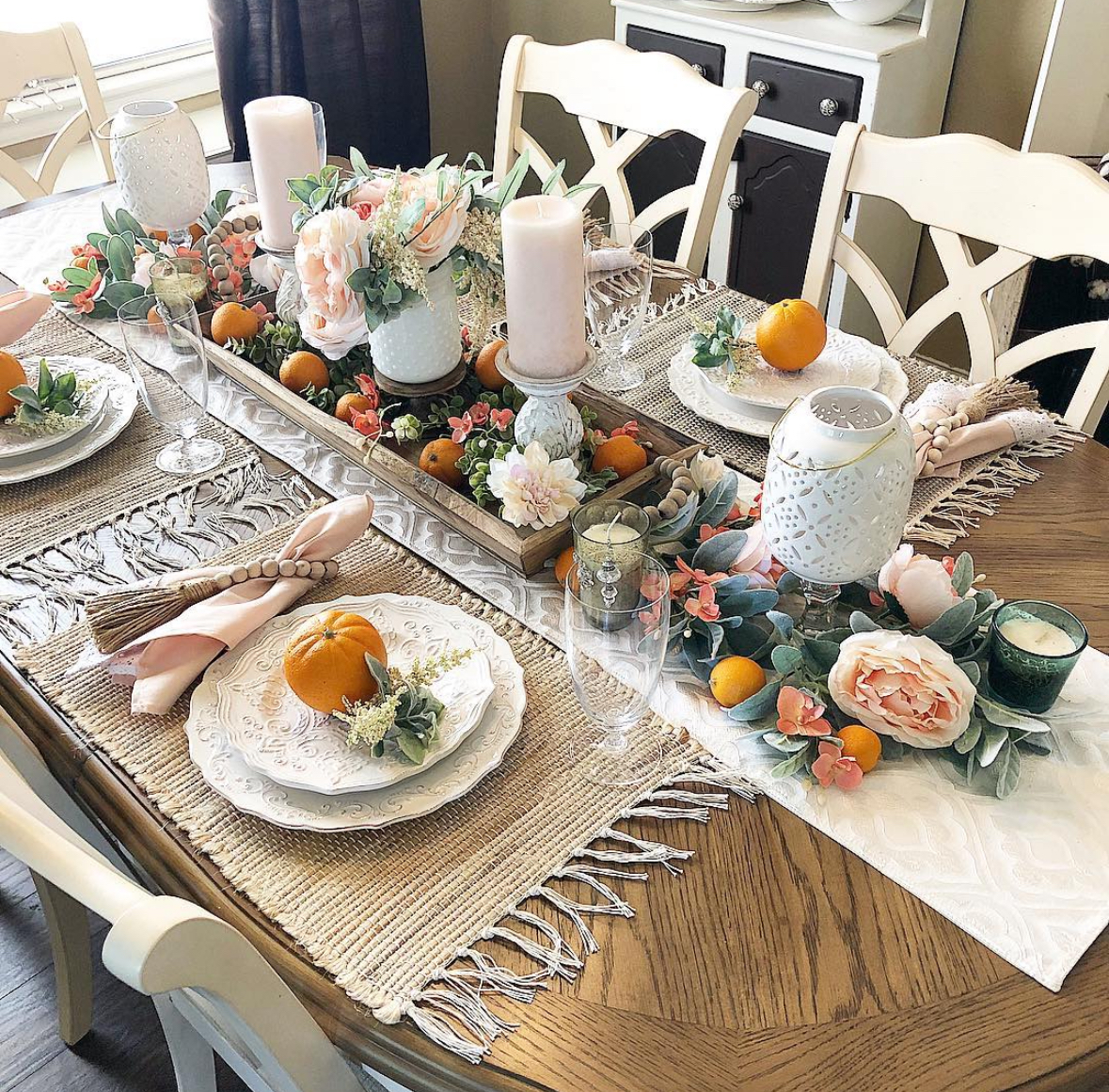 Fall tablescape with blush napkins, scalloped plates, and a tray of peonies and citrus.