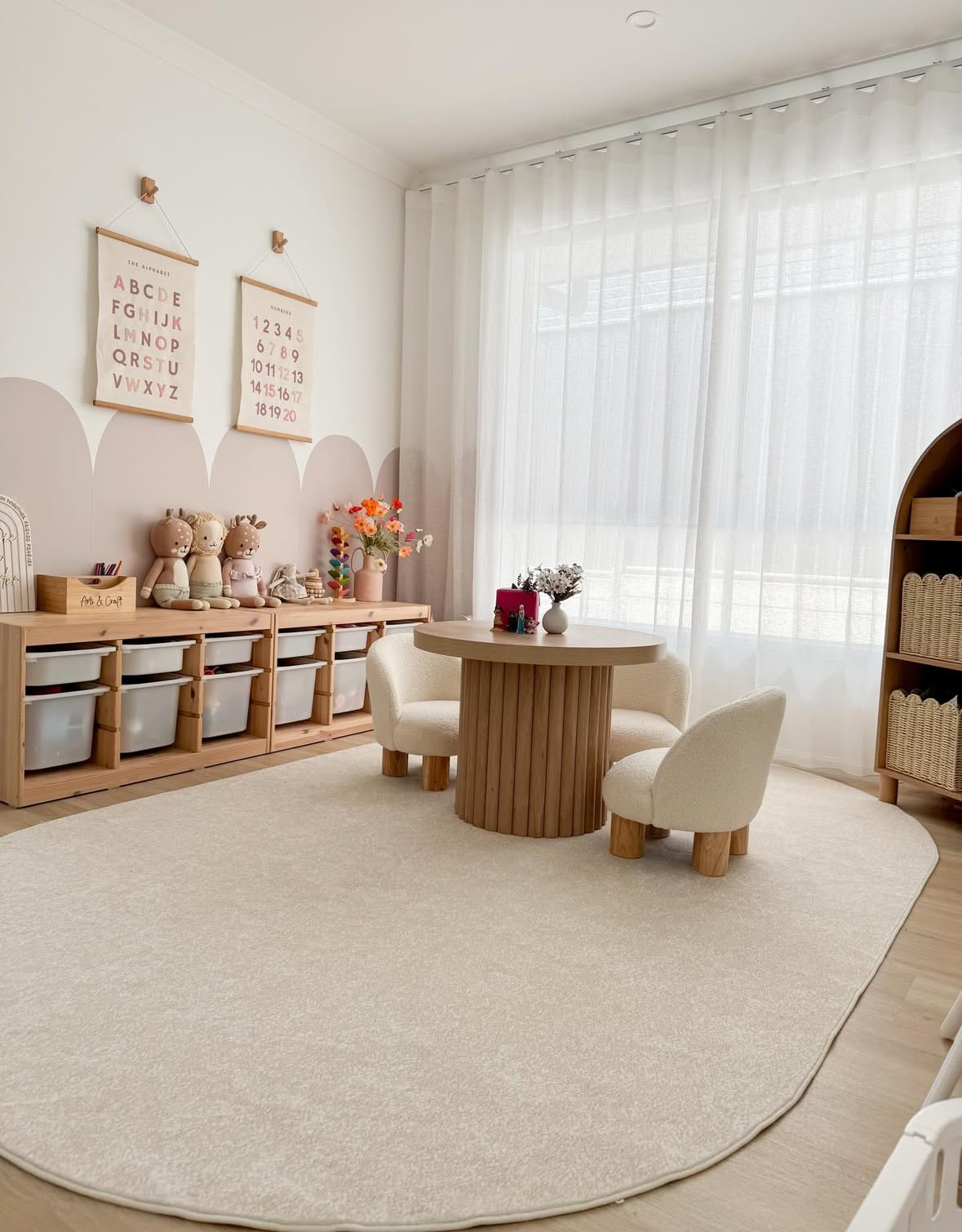 Neutral playroom with an oval rug and small round table creating a cozy craft and puzzle zone.