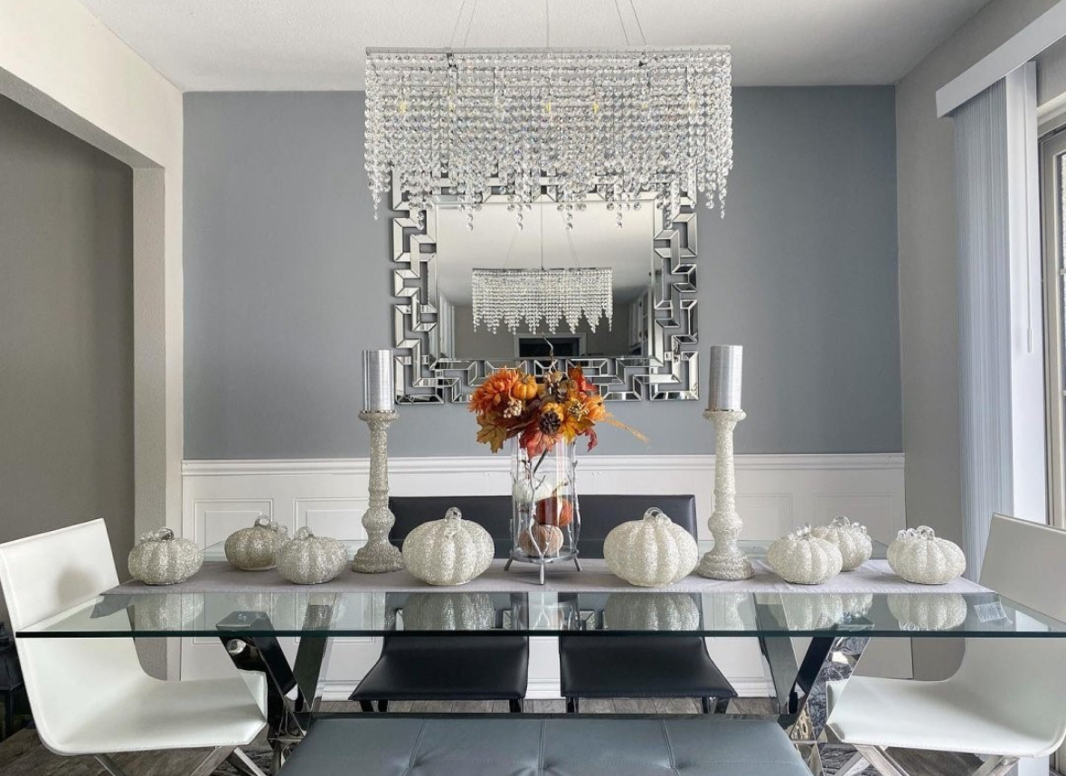 Glam glass table with glittered pumpkins, tall metallic candlesticks, and a chandelier.