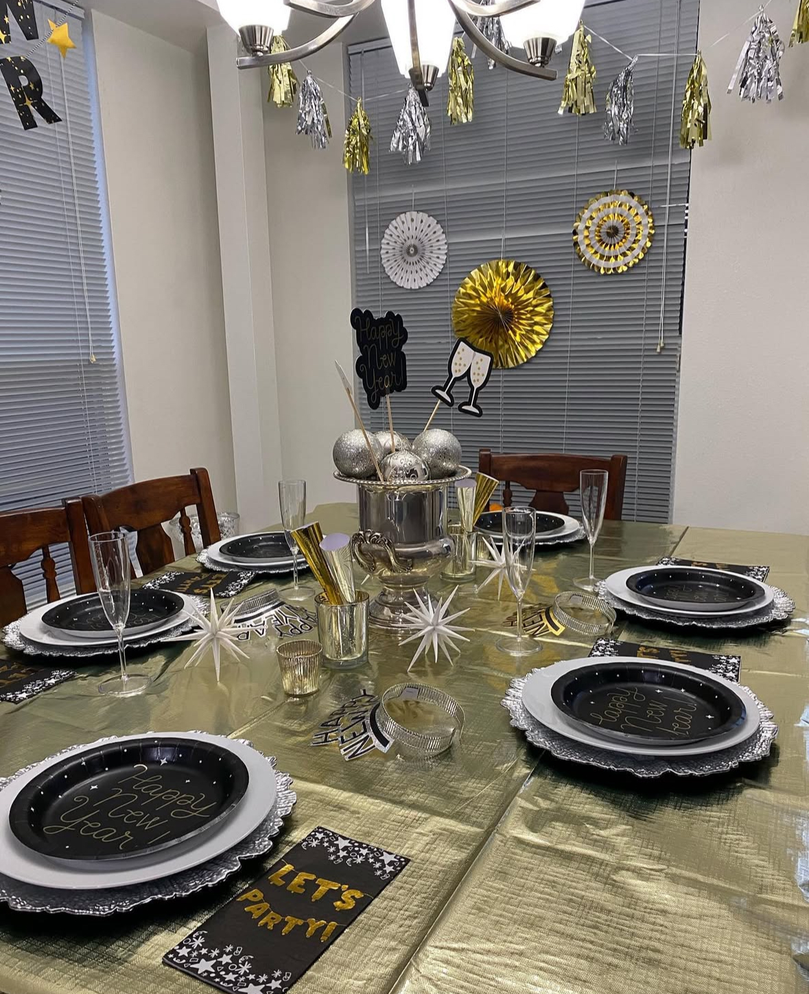 Gold tablecloth with black “Happy New Year” plates and star decor.