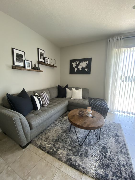 Collection of framed prints and wall art arranged above a grey sofa with black and white pillows