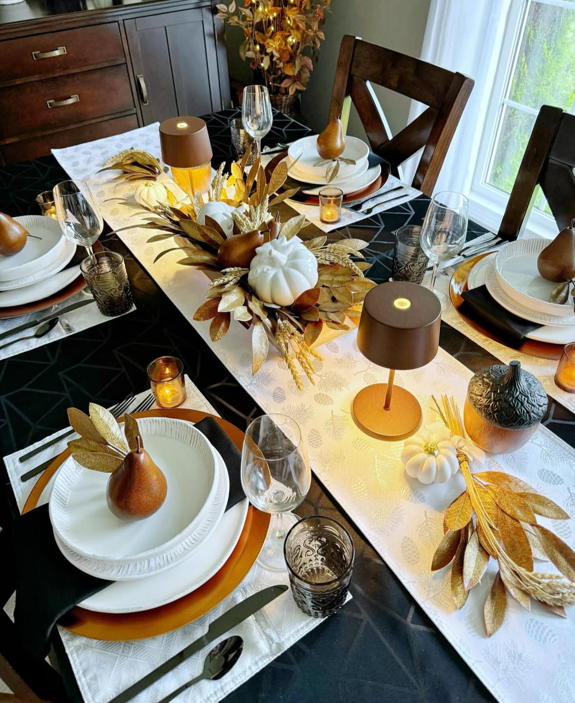 Elegant fall runner with mini lamps, white pumpkins, gilded leaves, and pear place cards.