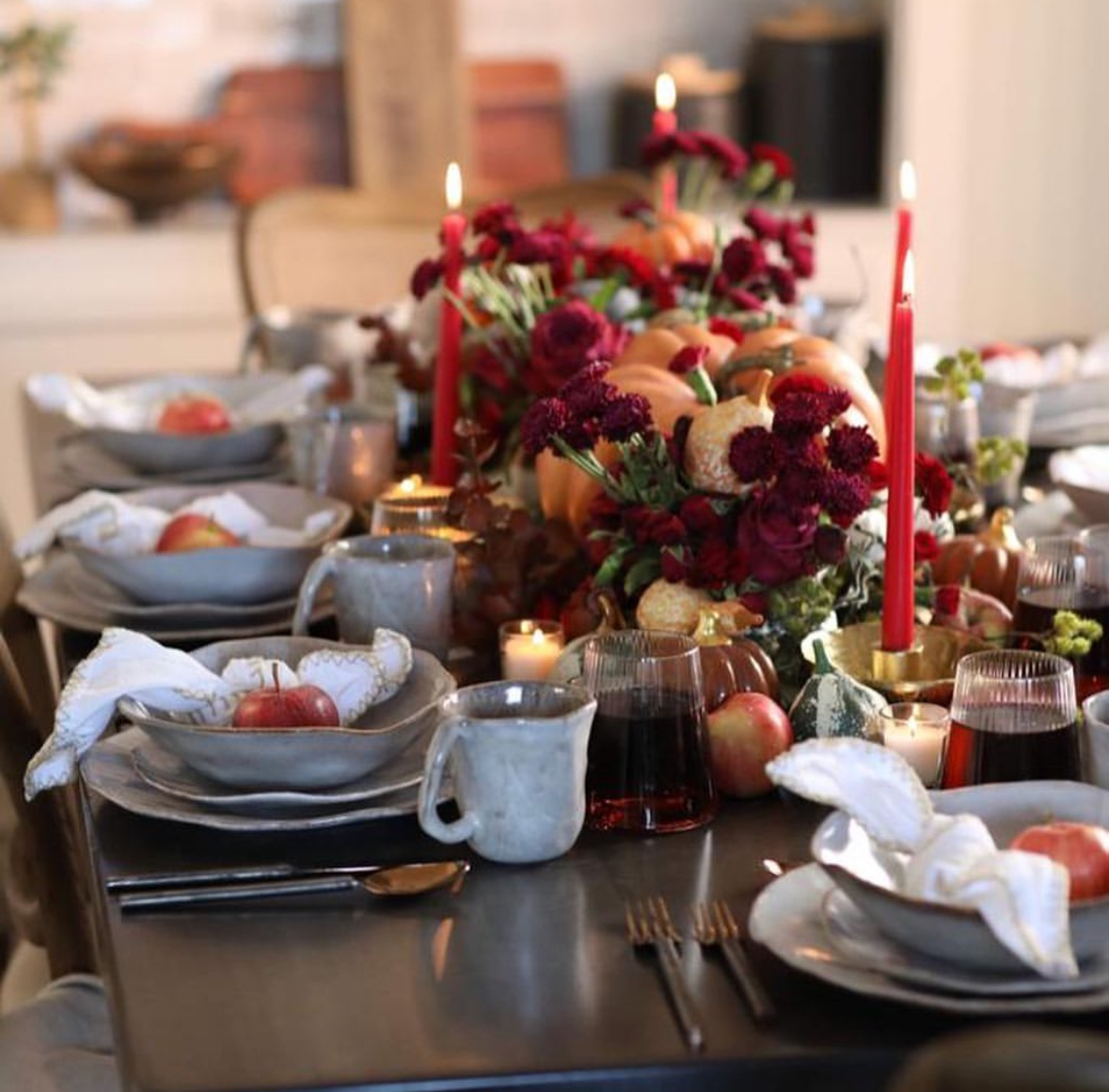 Dramatic fall setting with cranberry florals, tapered candles, and apples at each place.