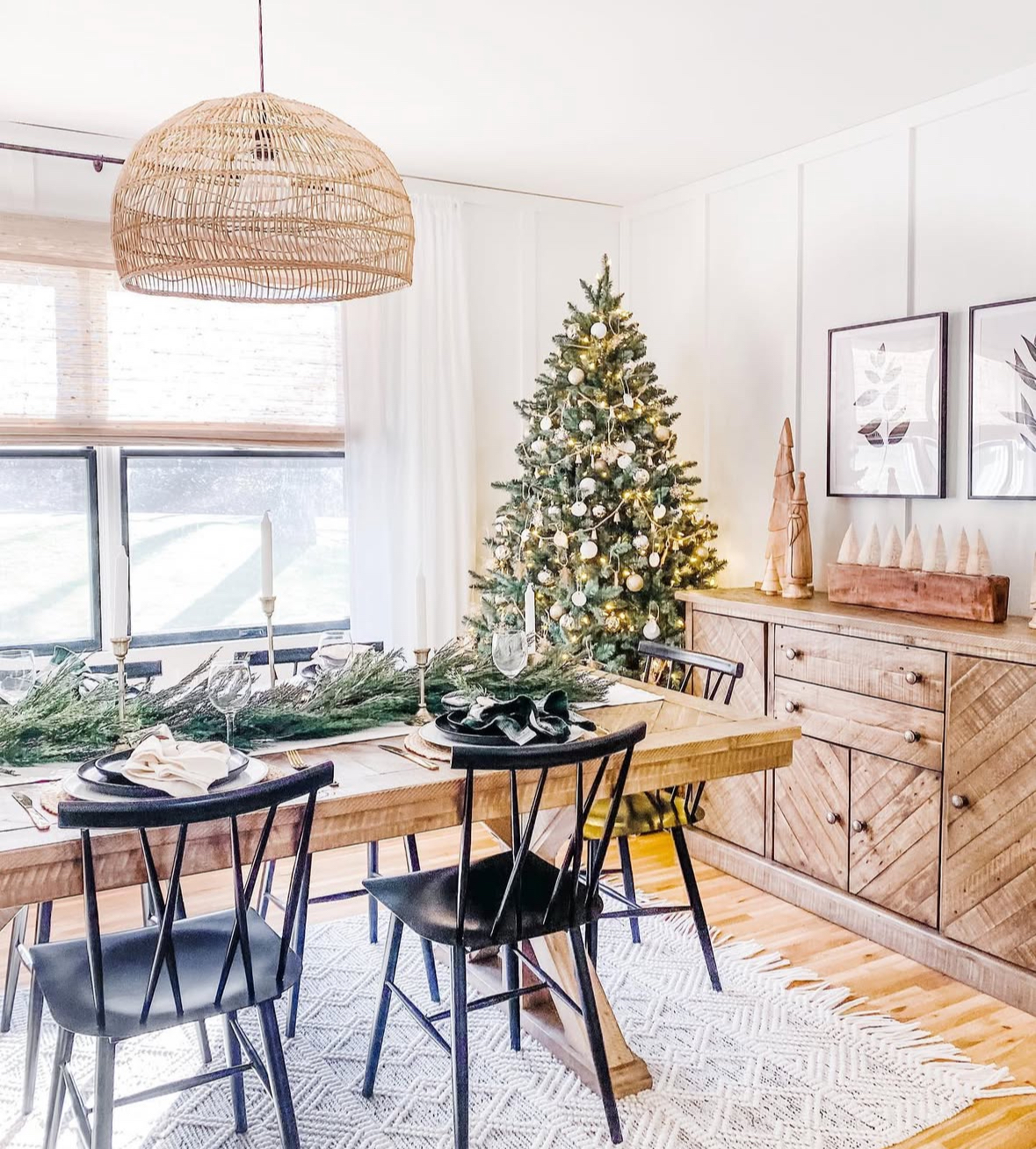 Modern wood-and-white space with greenery runner showing dining room Christmas decorating ideas.