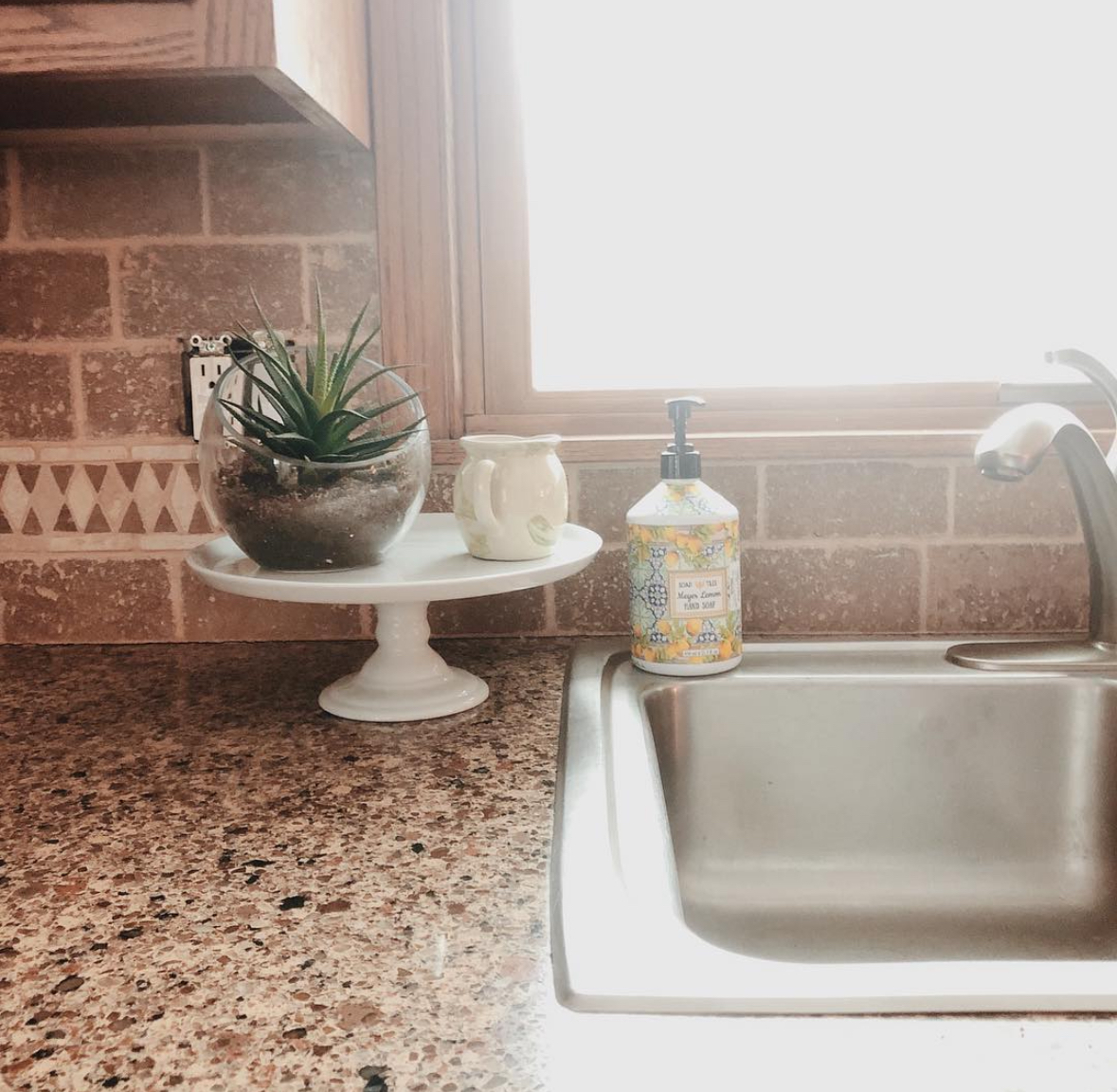 Sink area featuring a tan brick backsplash before renovation