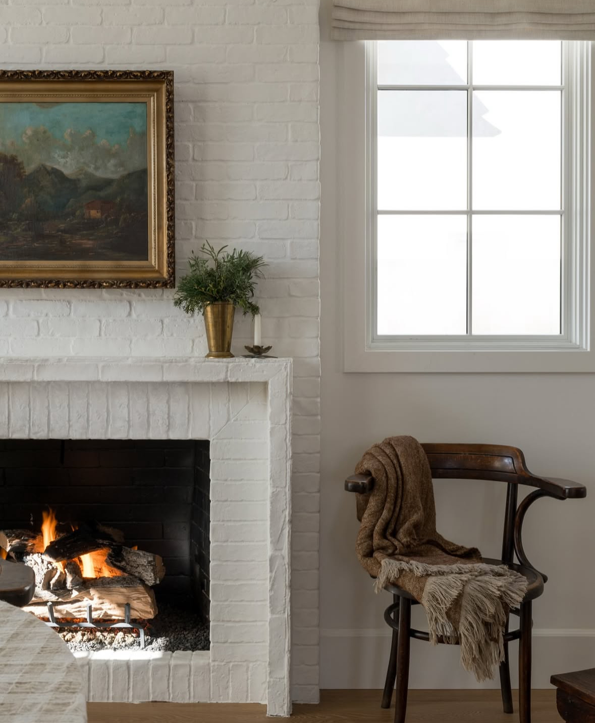 Classic whitewashed brick fireplace with brass accents